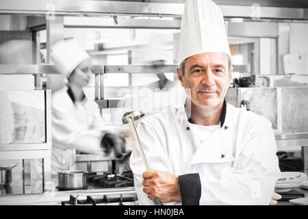 Chef holding ladle while smiling Stock Photo