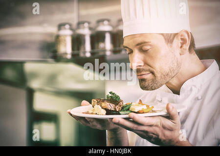Closeup of a male chef with eyes closed smelling gourmet food in the kitchen Stock Photo