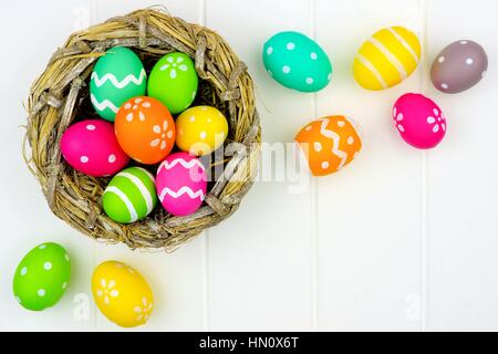 Springtime nest with colorful Easter Eggs against a white wood background Stock Photo