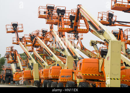 A field of powered access platforms or cherry pickers reaching for the sky Stock Photo