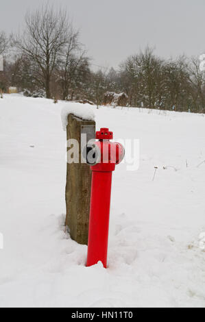 red pipe from hydrant on the snow covered field Stock Photo