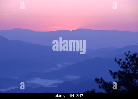 Layers of the smoky mountains with clouds and tree foreground during dramatic colorful sunset Stock Photo