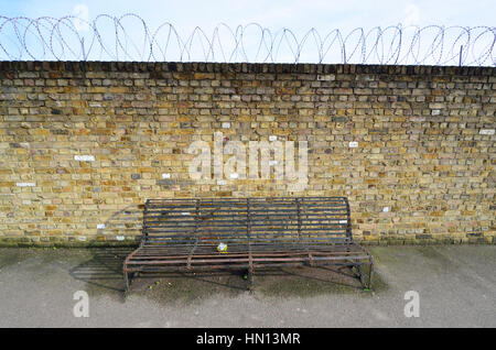 Faversham, Kent, England. Public bench in Bridge Street - wall with razor wire Stock Photo