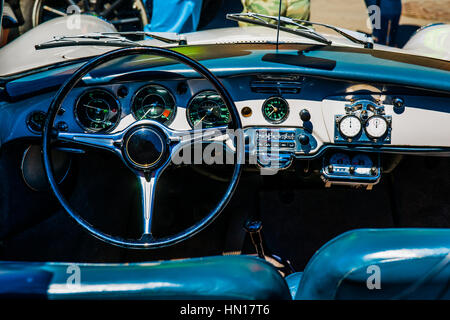 Color and beauty of vintage cars. Black steering wheel and a dashboard of an old European sport car. Stock Photo