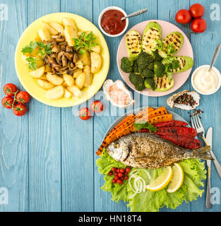 Delicious and nutritious meal rich in vitamins and minerals with fish and grilled vegetables: potatoes, mushrooms, carrot, tomato, broccoli, pepper, s Stock Photo