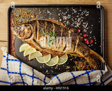 baked carp with spices and lemon on black pan Stock Photo