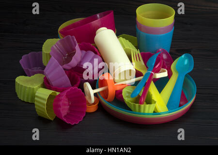 colored plastic tableware on a dark wooden background Stock Photo