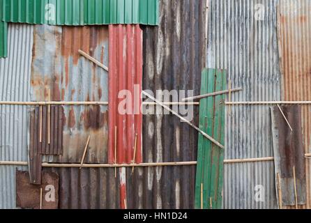 A wall made up of odd sheets of rusty colored/coloured corrugated iron sheets. Kompong Cham, Cambodia Stock Photo