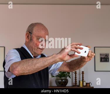 Senior elderly man taking photograph with i-phone mobile phone Stock Photo