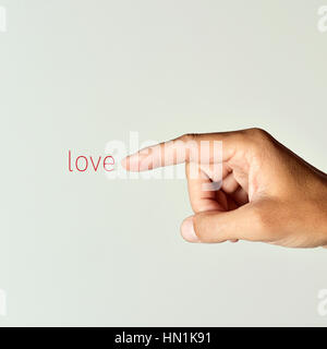 closeup of the forefinger of a young caucasian man pointing the word love, against an off-white background Stock Photo