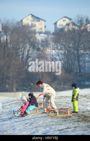 ZAGREB, CROATIA - JANUARY 15, 2017 : Children sledding down the hill in the presence of an adult woman at winter time in Zagreb, Croatia. Stock Photo