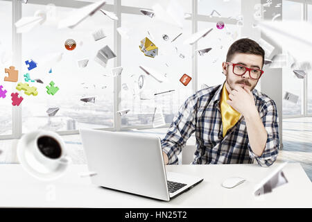 Young man in glasses and checked shirt working on laptop. Mixed media Stock Photo