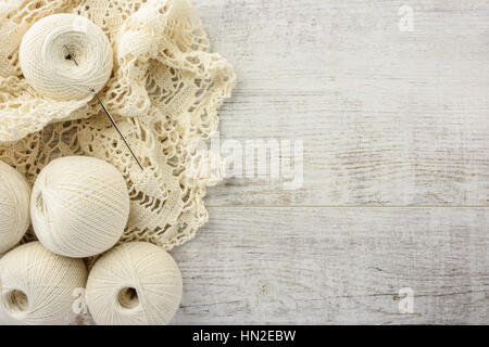 crochet tablecloth, crochet hooks and balls of cotton thread on a white wooden table. top view, copy space Stock Photo
