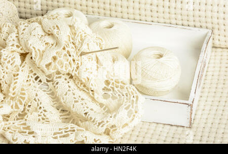 crochet tablecloth, crochet hooks and balls of cotton thread on a white woolen plaid Stock Photo