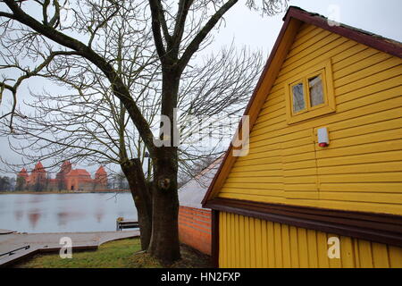 TRAKAI, LITHUANIA: Trakai castle built on an island of Lake Galve near Vilnius - a colorful wooden house in the foreground Stock Photo