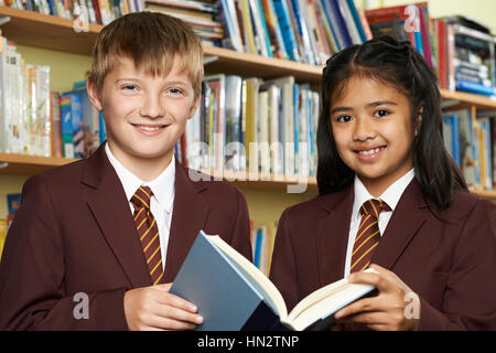 Pupils Wearing School Uniform Reading Book In Library Stock Photo