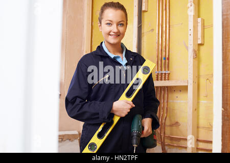 Portrait Of Female Builder With Spirit Level And Electric Drill Stock Photo