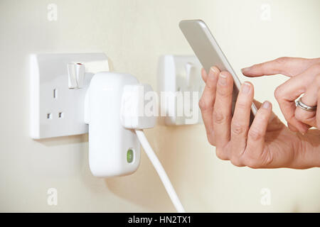Woman Controlling Smart Plug Using App On Mobile Phone Stock Photo