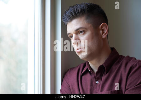Sad Man Suffering From Depression Looking Out Of Window Stock Photo