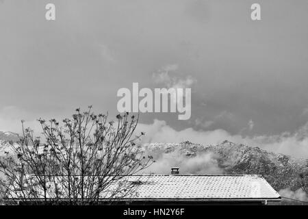 Snowy roof against background mountains in winter time. Subject captured over snow storm