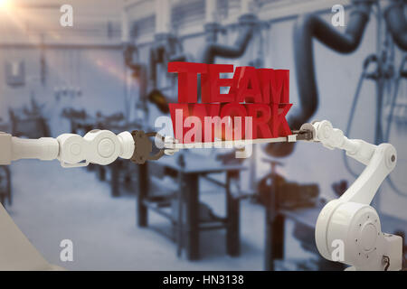 White robotic hand holding team work text against white background against various eqipments and pipes in factory Stock Photo