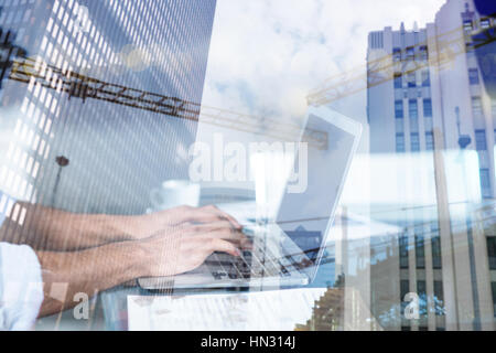 Crane and building construction site against businessman working on laptop Stock Photo