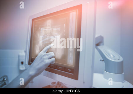 Xray of midsection of a human body against nurse pointing at ultrasonic monitor Stock Photo