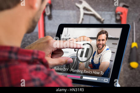Man using tablet on wooden table against portrait of handyman fixing washing machine Stock Photo
