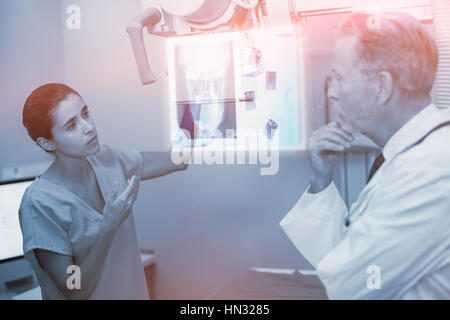 Overhead of a x-ray of a human skull against nurse interacting with doctor in x-ray room Stock Photo