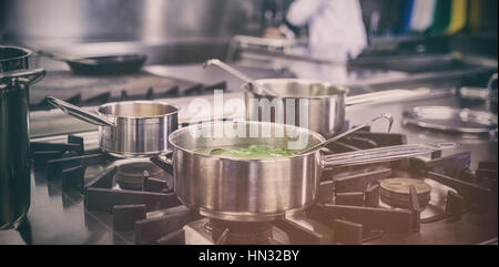 Different pots cooking on hotplate in professional kitchen Stock Photo
