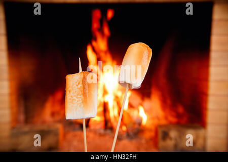 Two marshmallows on sticks being roasted by the fire Stock Photo