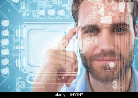 Man with finger pointing to head against close-up of circuit board Stock Photo