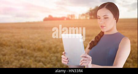 Beautiful woman using digital tablet against sky over golden fields Stock Photo