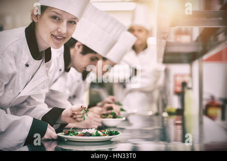 Happy chef looking up from preparing salad in culinary class Stock Photo