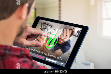 Man using tablet on wooden table against portrait of plumber fixing under sink Stock Photo