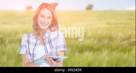 Pretty hipster using tablet  against green meadow Stock Photo