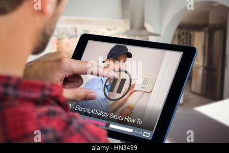 Man using tablet on wooden table against portrait of handyman fixing alarm system Stock Photo