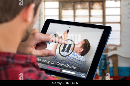 Man using tablet against handyman using cordless drill to ceiling Stock Photo