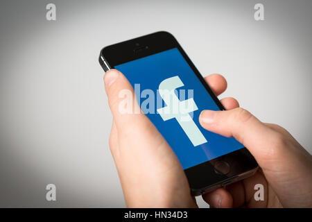A teenage boy using Facebook on an iPhone Stock Photo