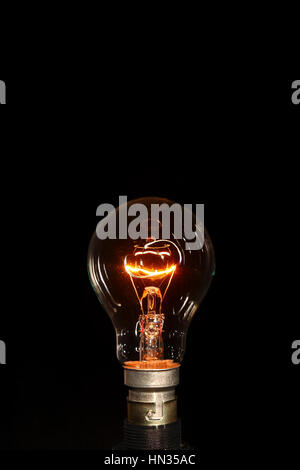 Conceptual image of a dimmed light bulb synonymous with an idea, intellect or invention isolated on a black background Stock Photo