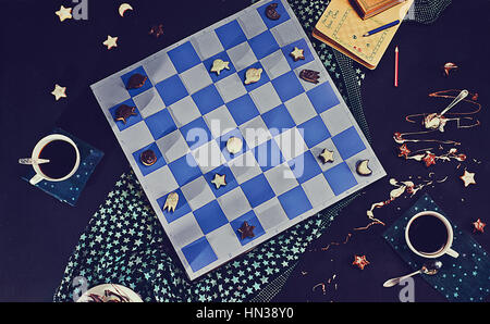 A board of Space Chess with figures of comets and starships made from chocolate glazed cookies. Stock Photo