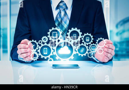 Businessman holding a cloud connected to many objects on a virtual screen concept about the internet of things. Stock Photo