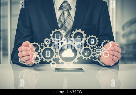 Businessman holding a cloud connected to many objects on a virtual screen concept about the internet of things. Stock Photo