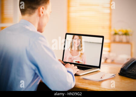 Businessman working on his laptop against woman having breakfast in kitchen Stock Photo