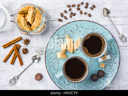 Tasty and healthy almond cookies, rich in vitamins, minerals in a glass jar, cups of coffee, almonds, chocolates, cinnamon, star anise and sugar on wh Stock Photo