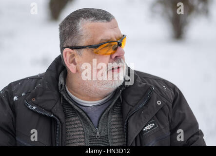 Outdoor portrait of bearded Caucasian senior in yellow sun glasses at winter season Stock Photo