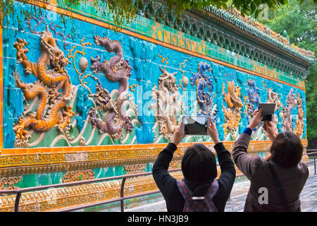 Tourists photographing Nine Dragon Wall in Beihai Park, Beijing, China Stock Photo