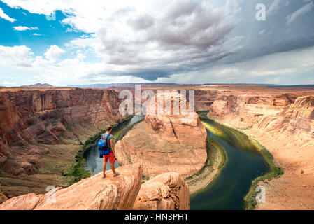 Young man on a rock, Horseshoe Bend, bend of the Colorado River, King Bend, Glen Canyon National Recreation Area, Page, Arizona Stock Photo