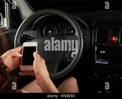 woman driver texting via smartphone isolated on black Stock Photo