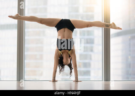 Young attractive woman in dance pose against floor window, hands Stock Photo